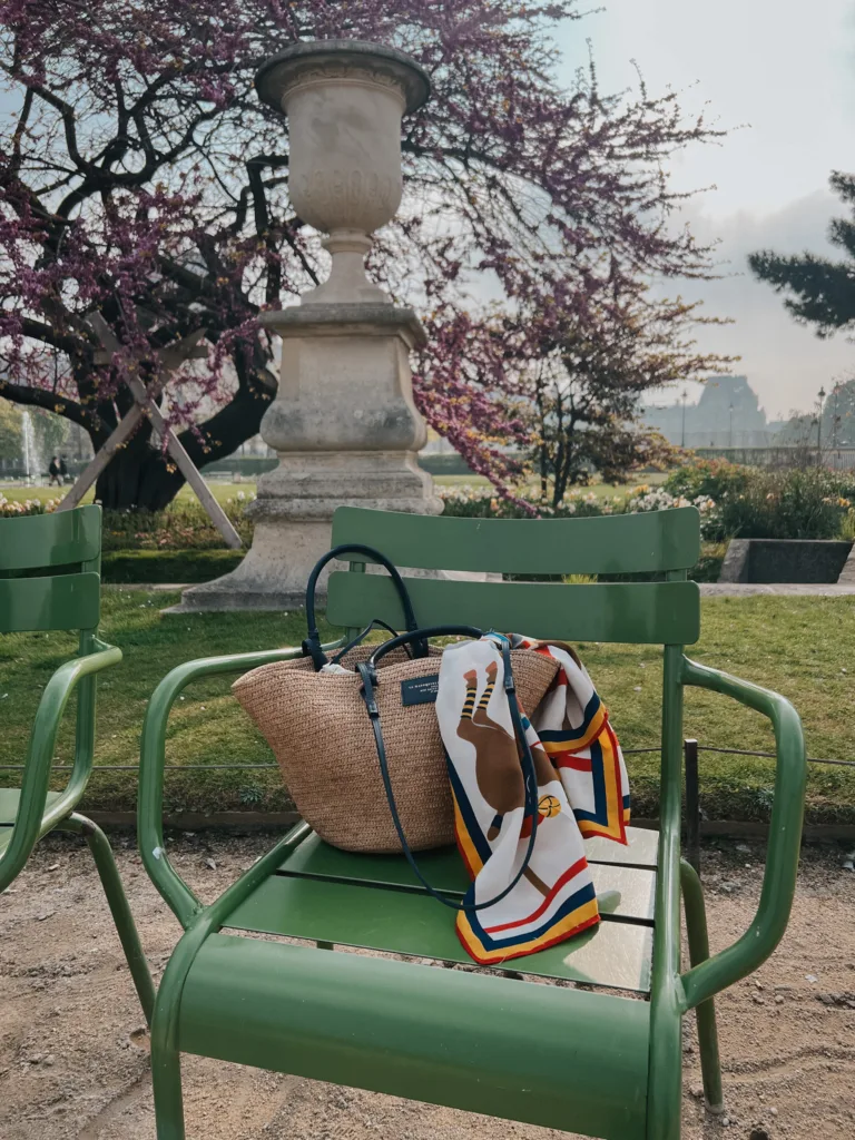 Basket bag sitting on a green chair with a scarf in the Tuileries.