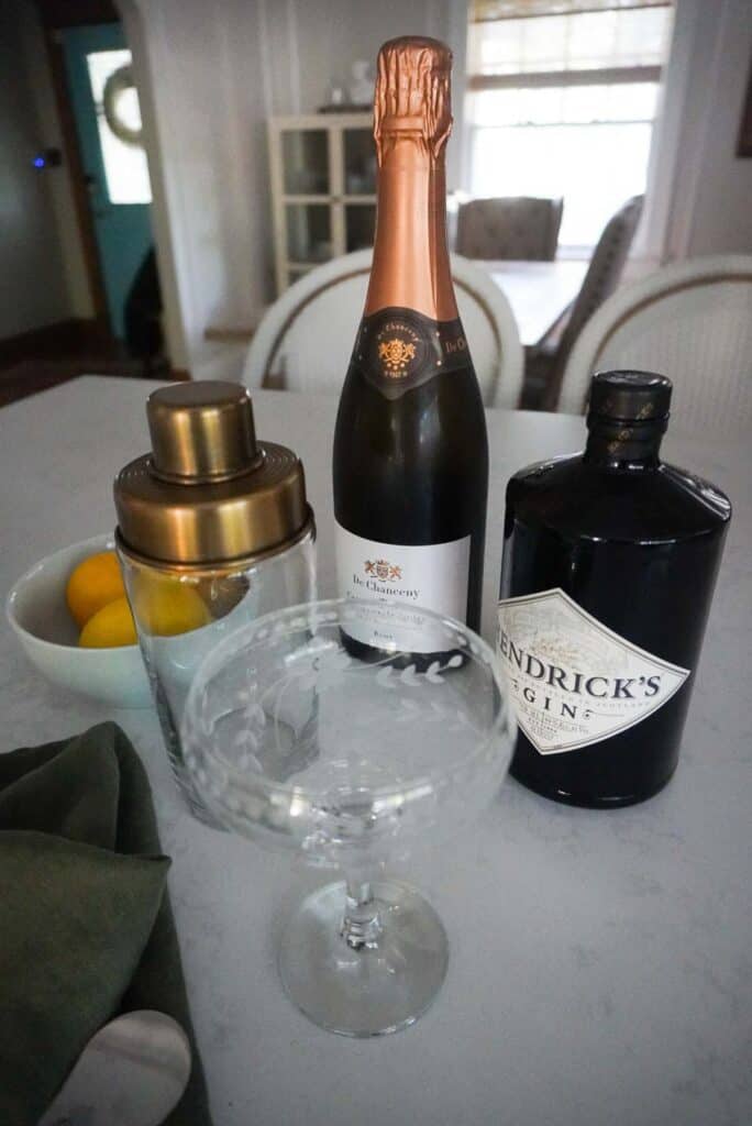 Shaker, champgane, gin, and a coupe sitting on a counter