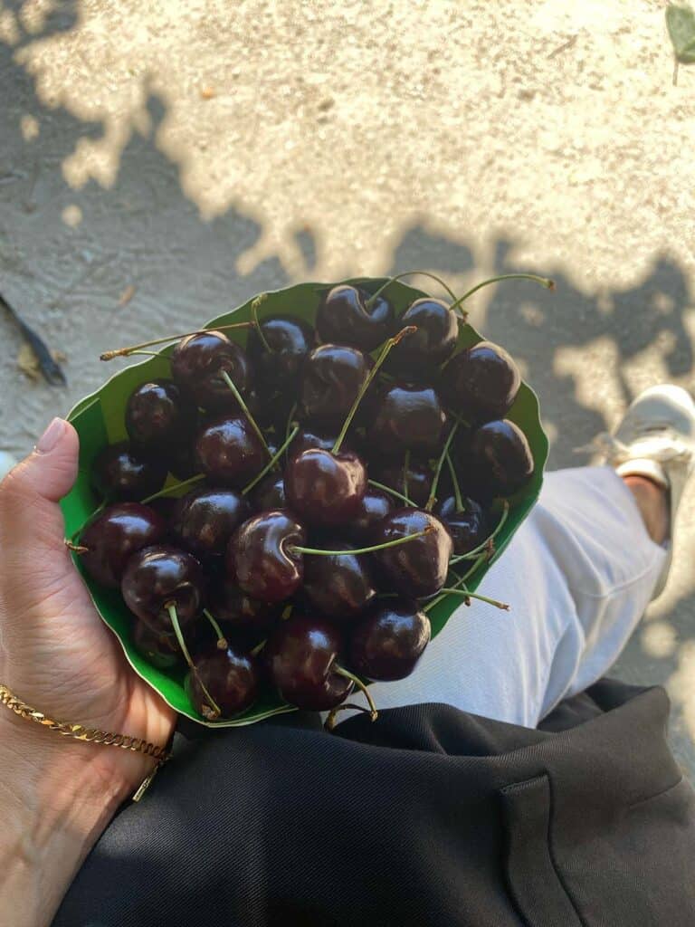holding a basket of cherries in a park 