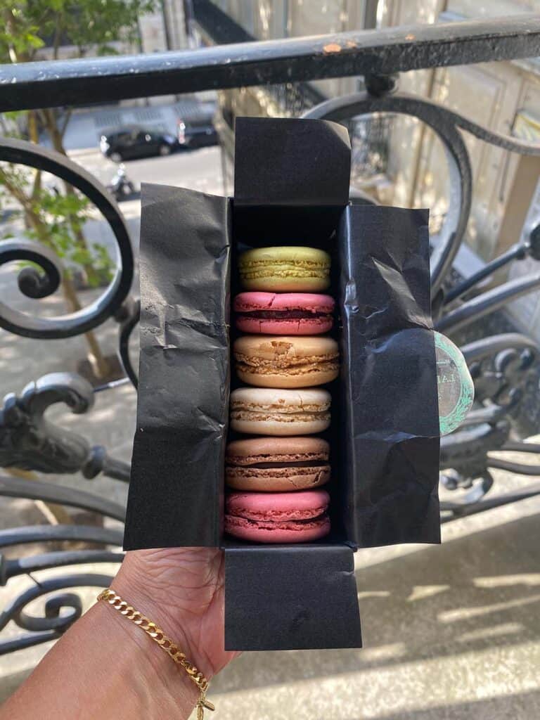 holding a black box with 6 macarons from Laduree Paris
