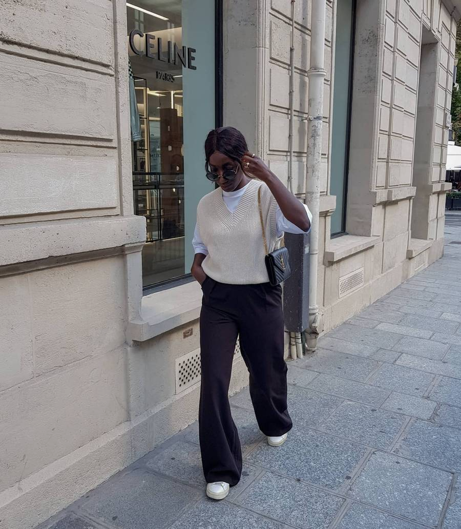 Girl wearing black trousers and a vest walking down street