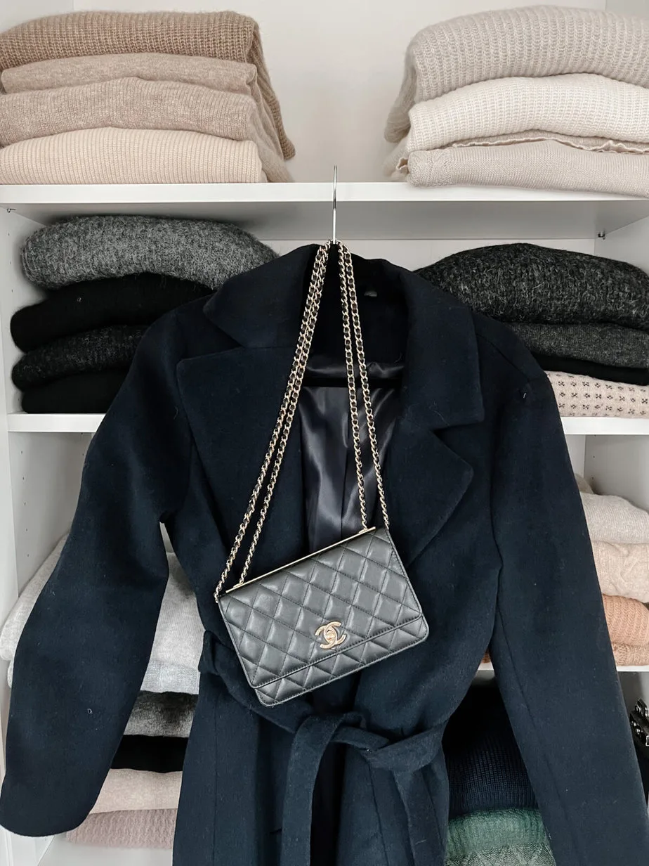 navy coat with purse and sweaters in the background