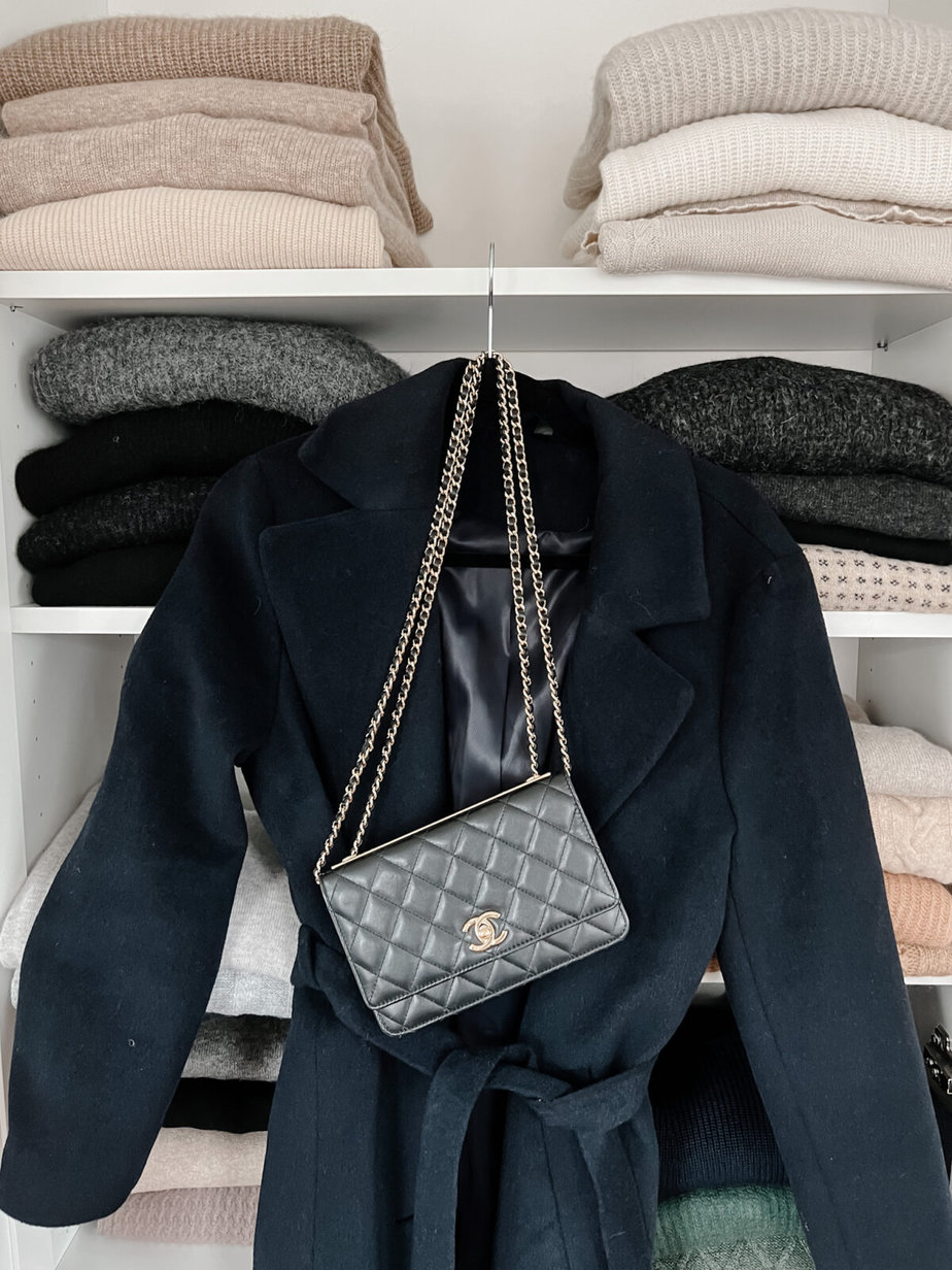 navy coat with purse and sweaters in the background
