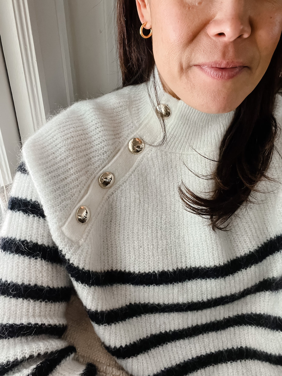 close up of black and white sweater on a girl but you can only see half her face.