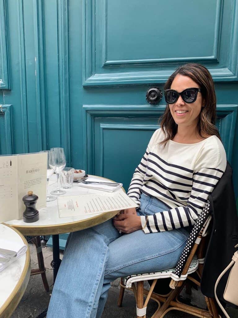 Wearing a stripe top sitting in front of blue door in Paris