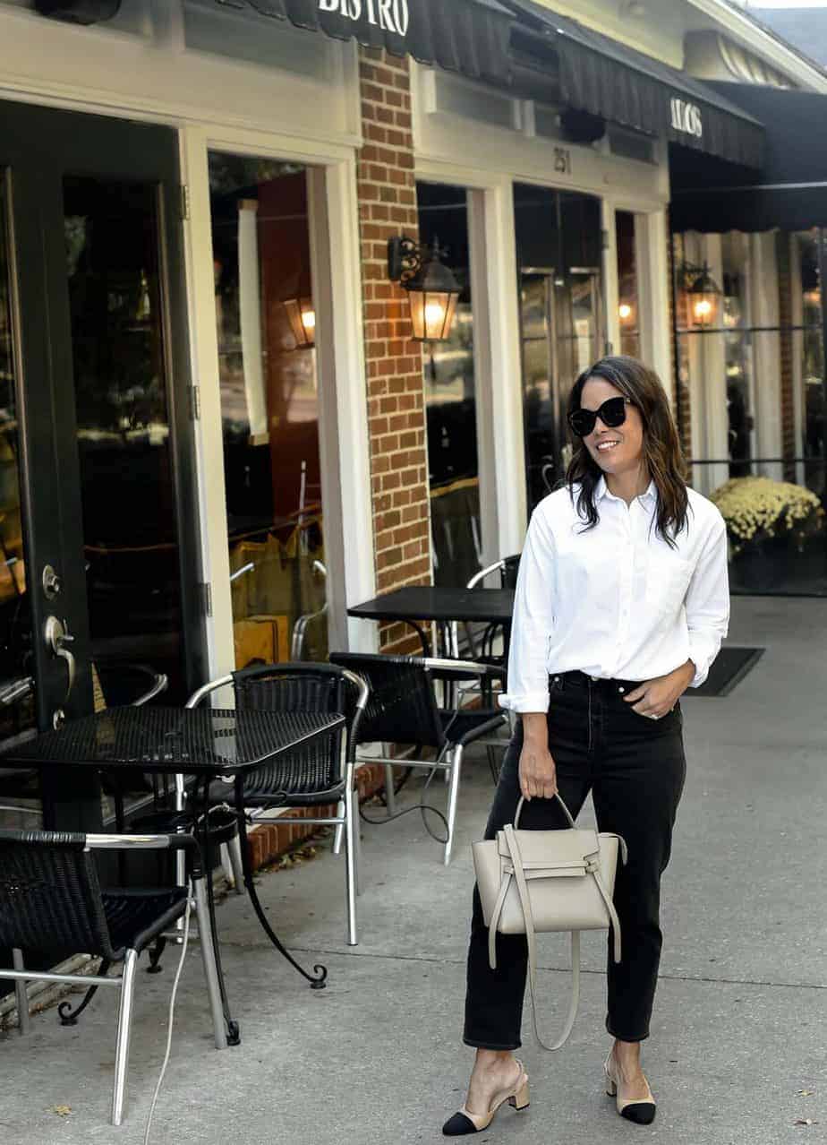Standing in front of restaurant in white button down with black jeans , grey purse, and black and tan heels