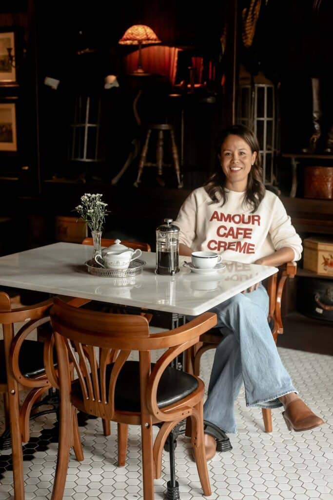 Sitting at a marble table in a restaurant with a sweatshirt on drinking french press coffee