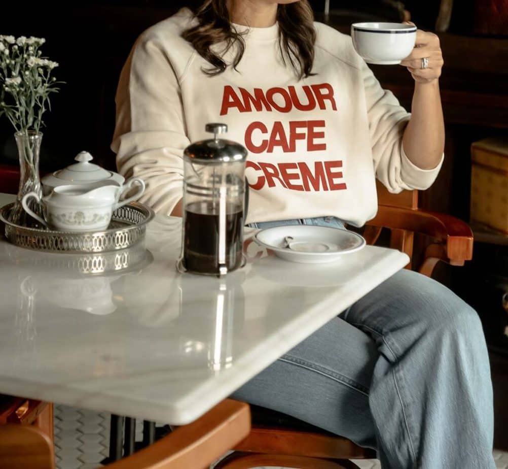 Close up of sweatshirt and french press coffee sitting in a restaurant