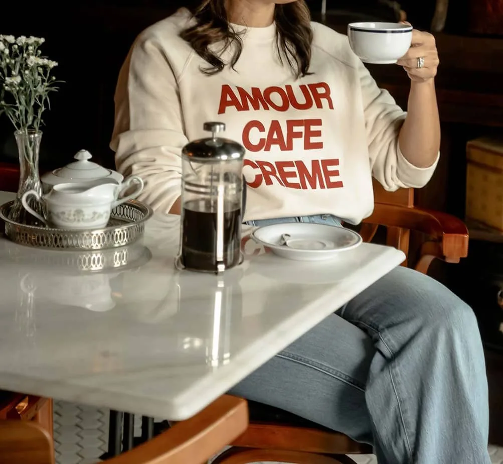 Close up of sweatshirt and french press coffee sitting in a restaurant