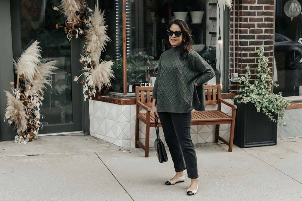 Standing wearing green sweater with sunglasses, black jeans, and flats