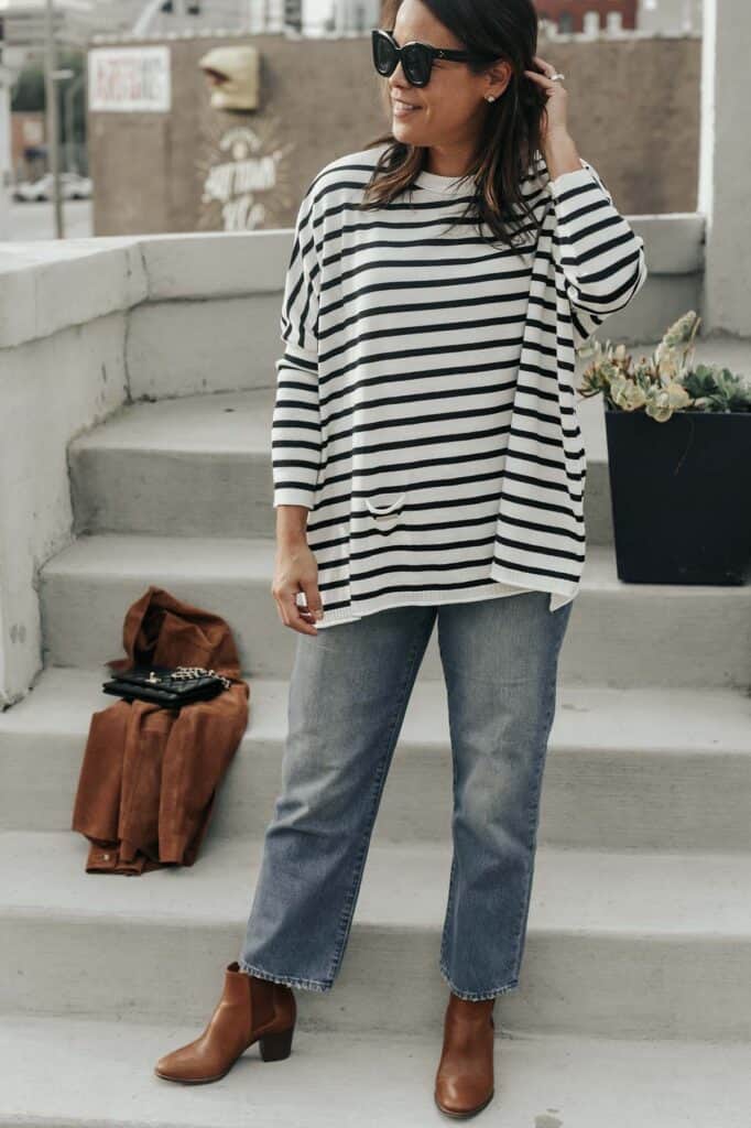 Standing with hand on hair wearing a navy and white striped top
