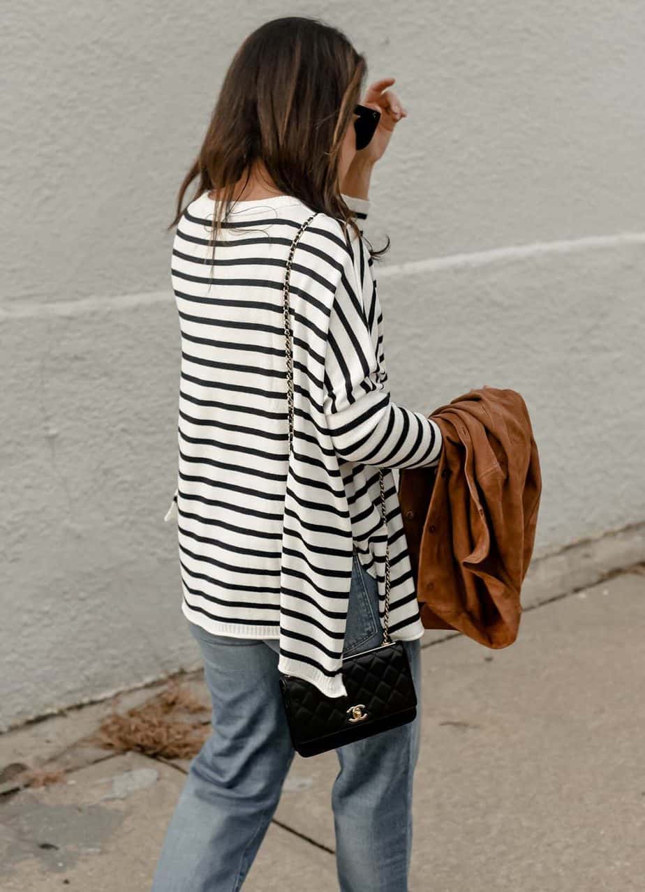 Walking down the street wearing a navy and white top with suede jacket in hand