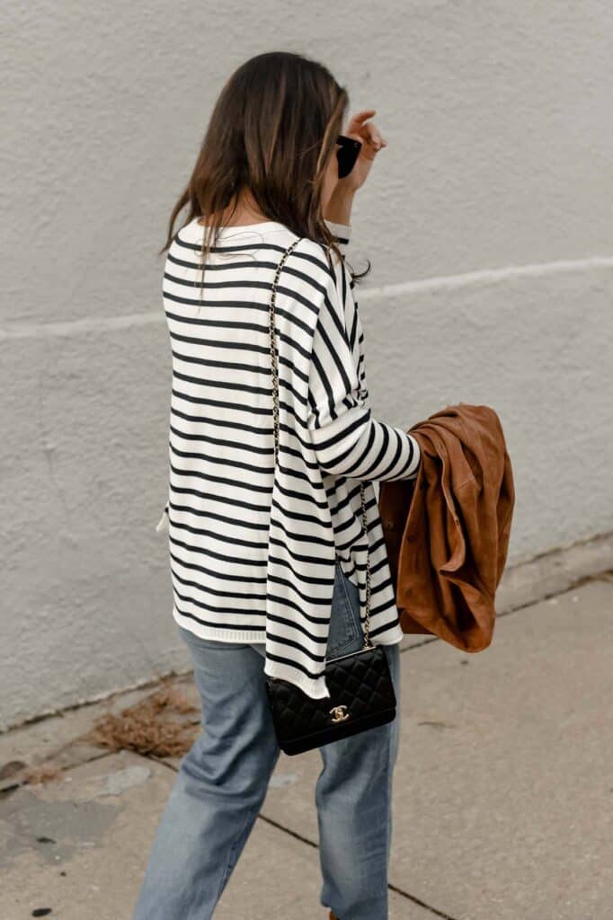 Walking down the street wearing a navy and white top with suede jacket in hand