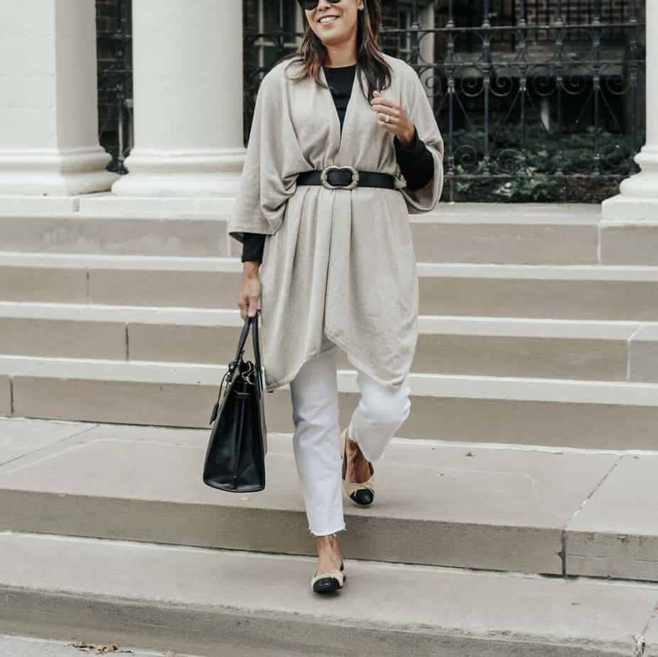 walking down stairs wearing travel wrap with white jeans, black bag, and flats