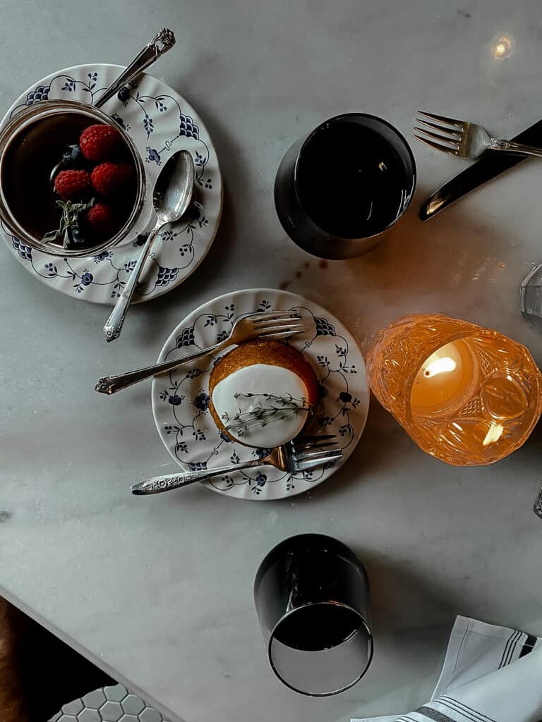 Two desserts sitting on blue and white plates at a restaurant on marble table with candelight