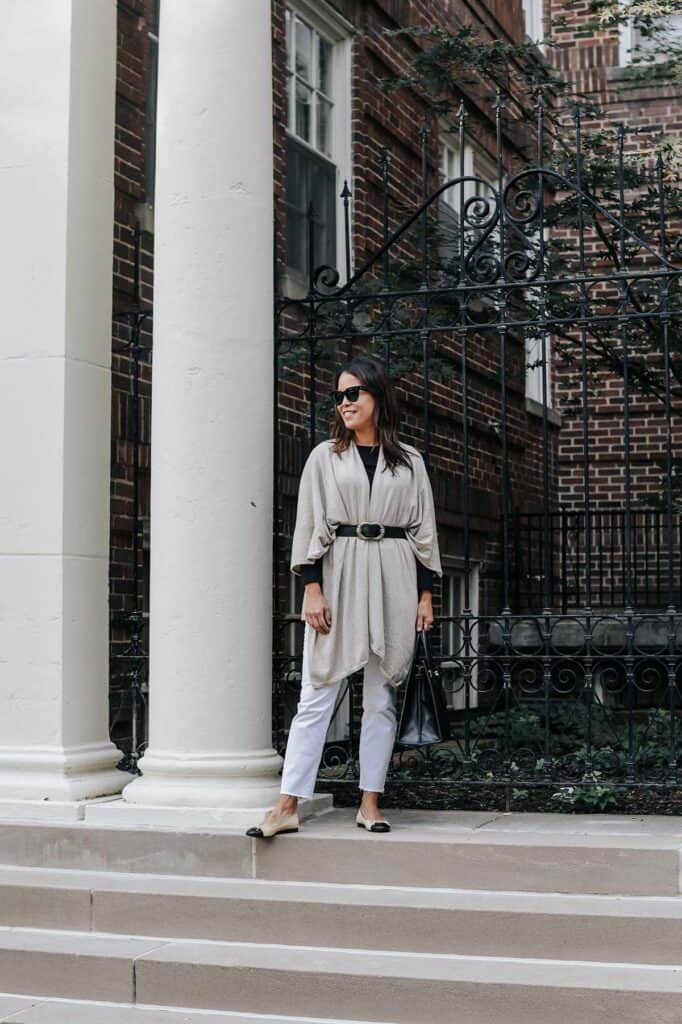 wearing wrap with white jeans standing in front of a column 