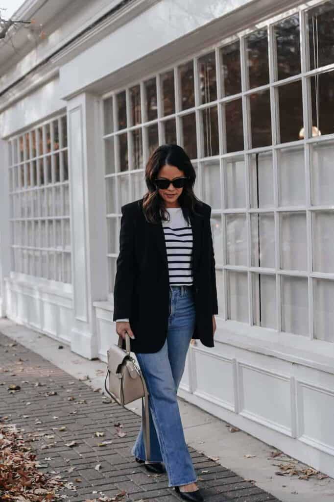 wearing stripe top with black blazer looking down onto ground