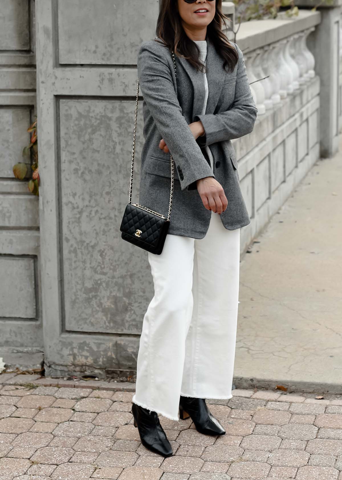 wearing grey blazer and white jeans standing on a bridge 