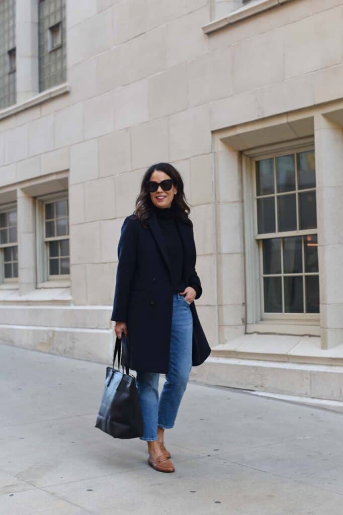 walkind down the street with cuyana leather tote and navy coat