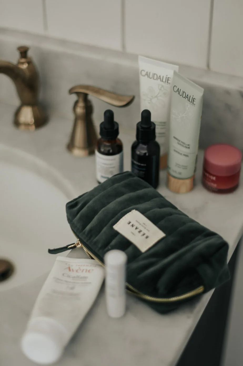 makeup sitting on a marble counter with green makeup bag