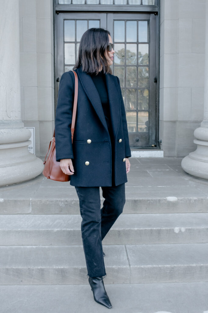Lady wearing navy jacket with black denim, brown bag | A Guide To Sézane Sizing
