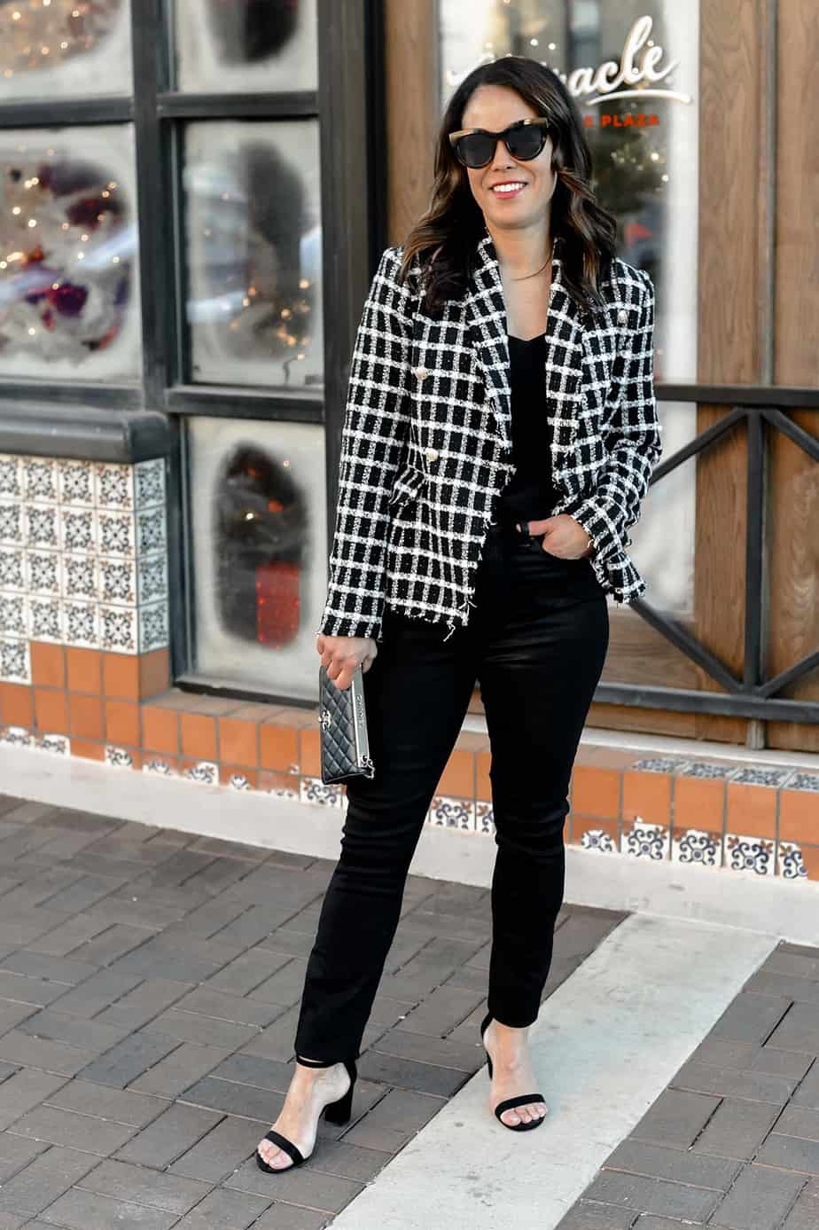 wearing black jeans, plaid blazer and holding black bag
