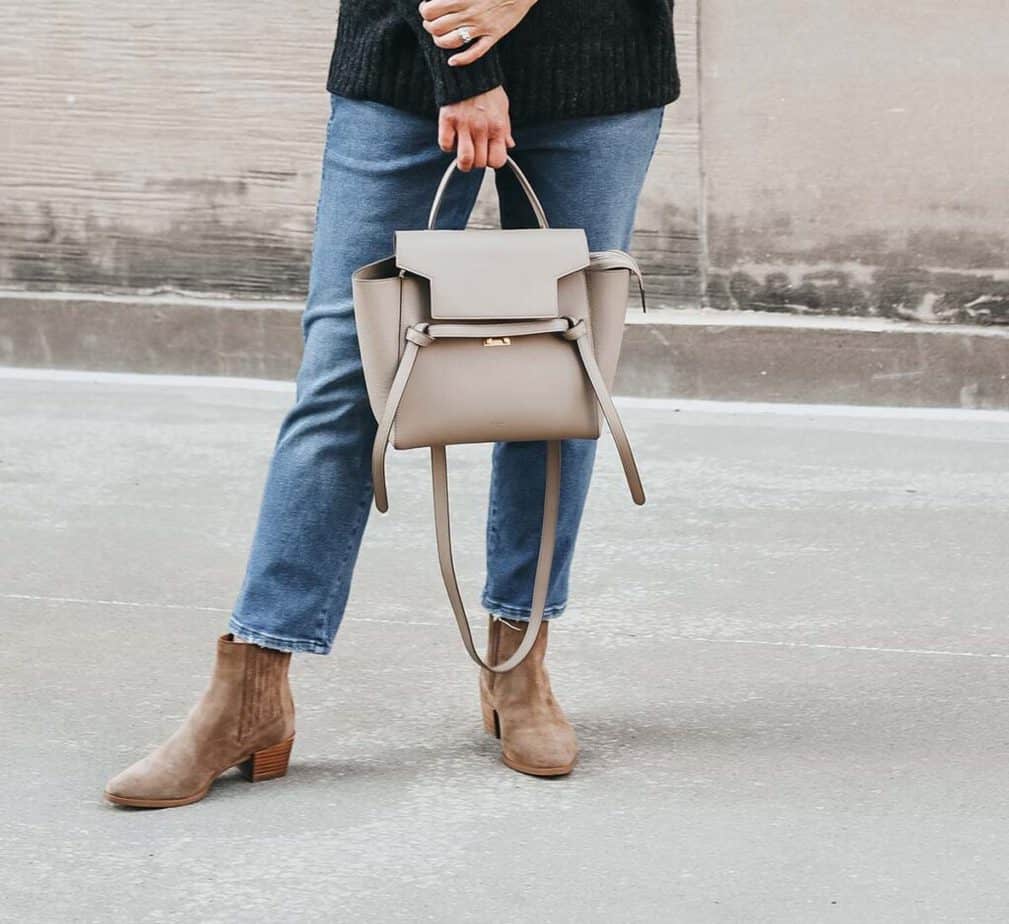 wearing booties holding grey purse
