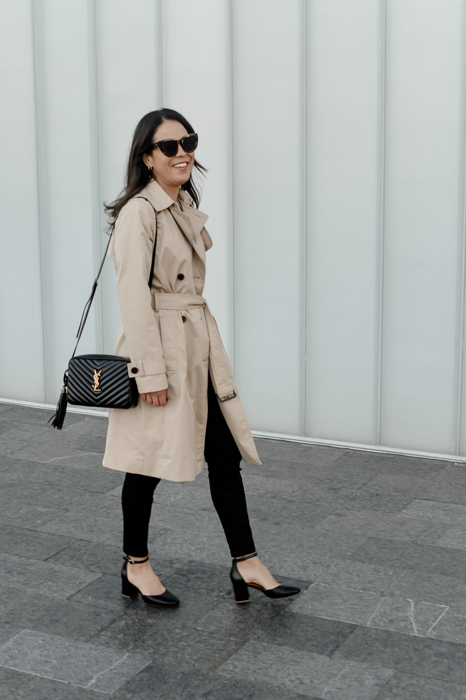 Wearing trench coat, black purse, pants, and black shoes