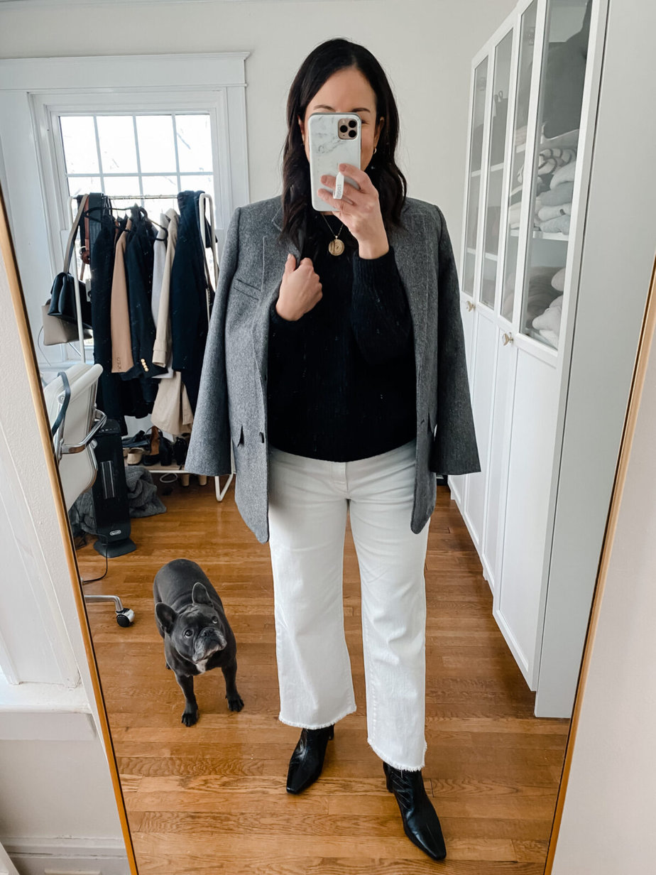 Wearing white jeans, grey blazer, black sweater taking a selfie in mirror