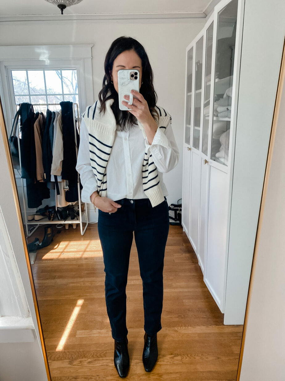 standing wearing white button down white stripe sweater and black jeans