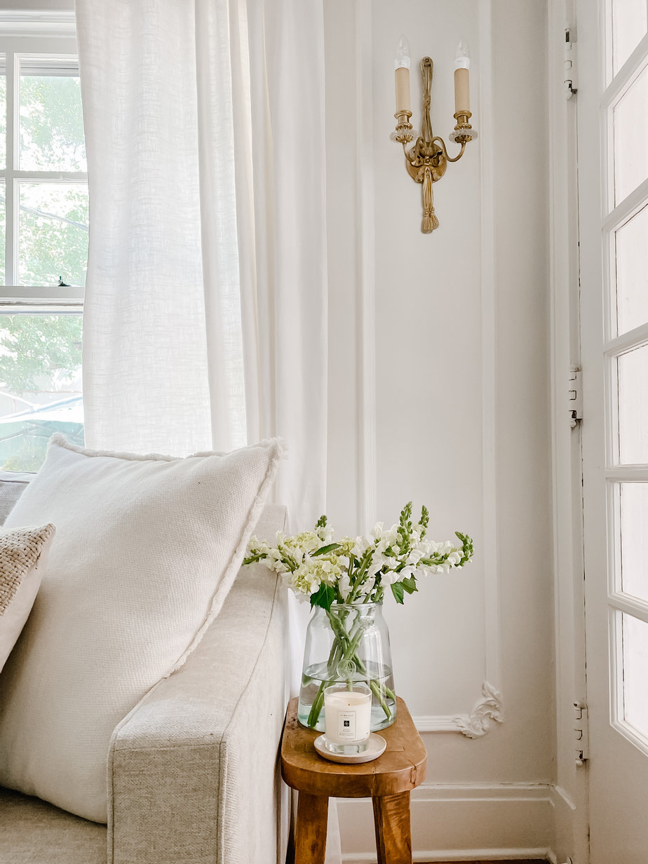 flowers in a vase with white walls and candle