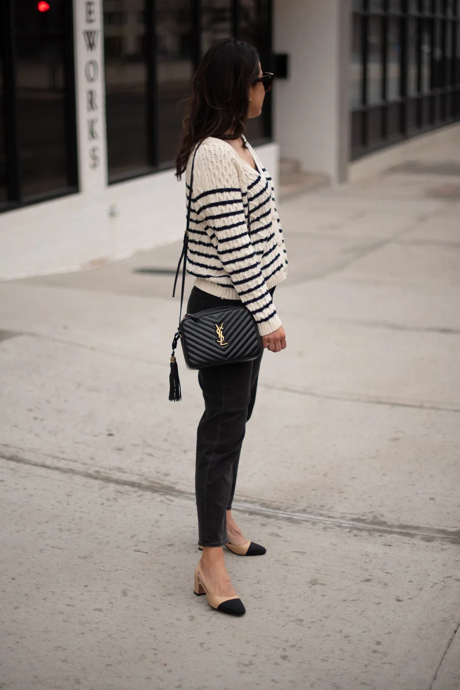standing on street with black jeans and stripe sweater