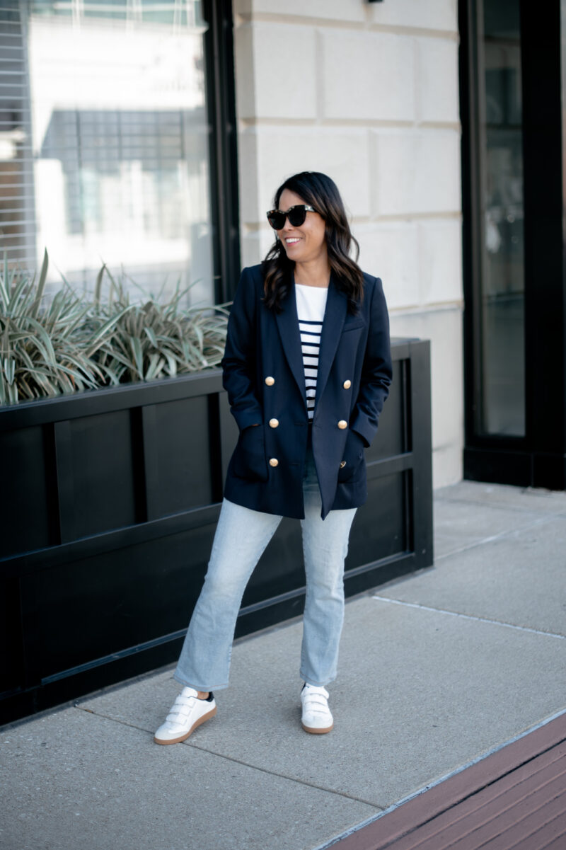 wearing navy blazer, jeans, and stripe top and sneakers