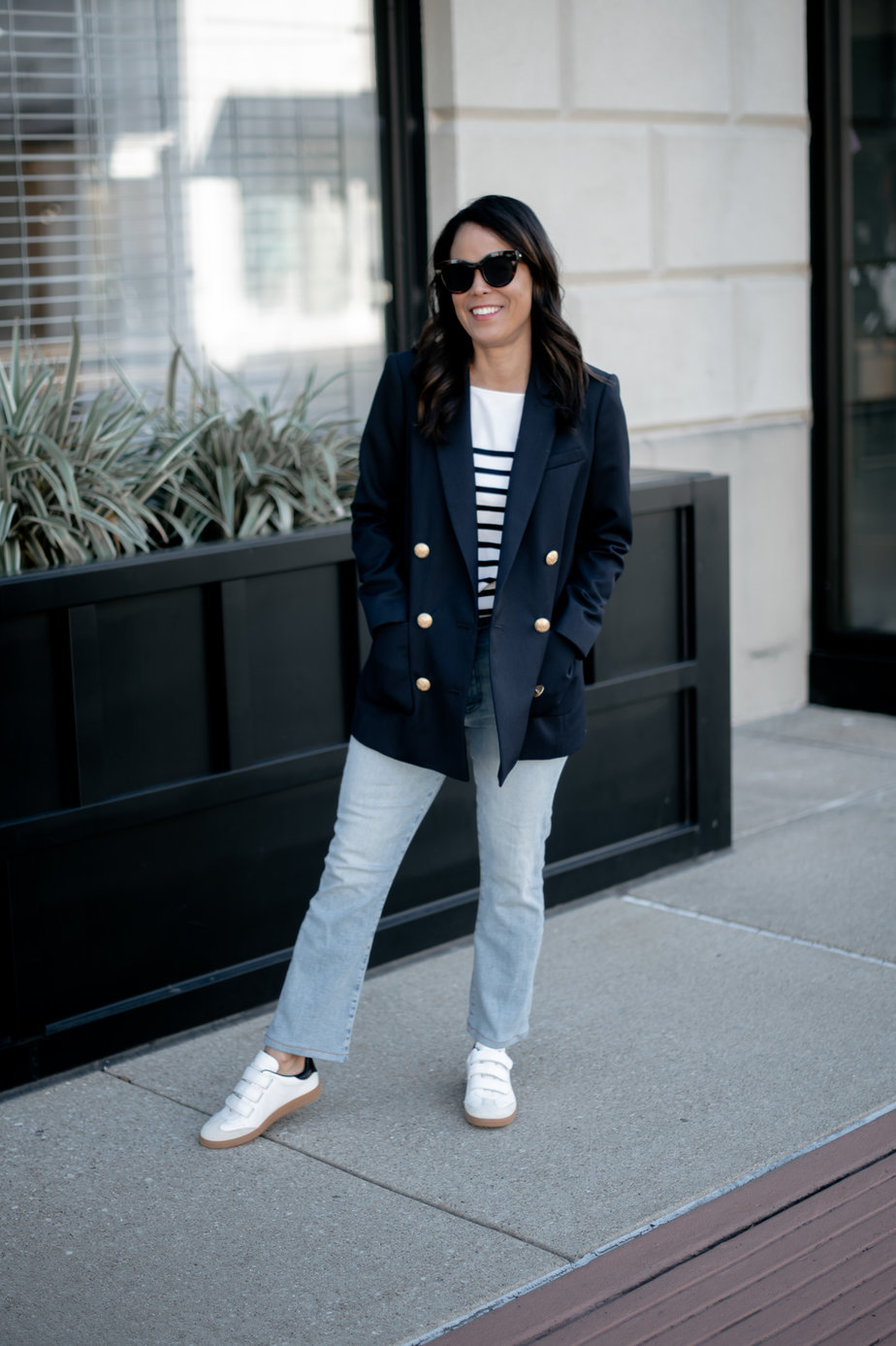 wearing navy blazer with stripe top, jeans, and sneakers 