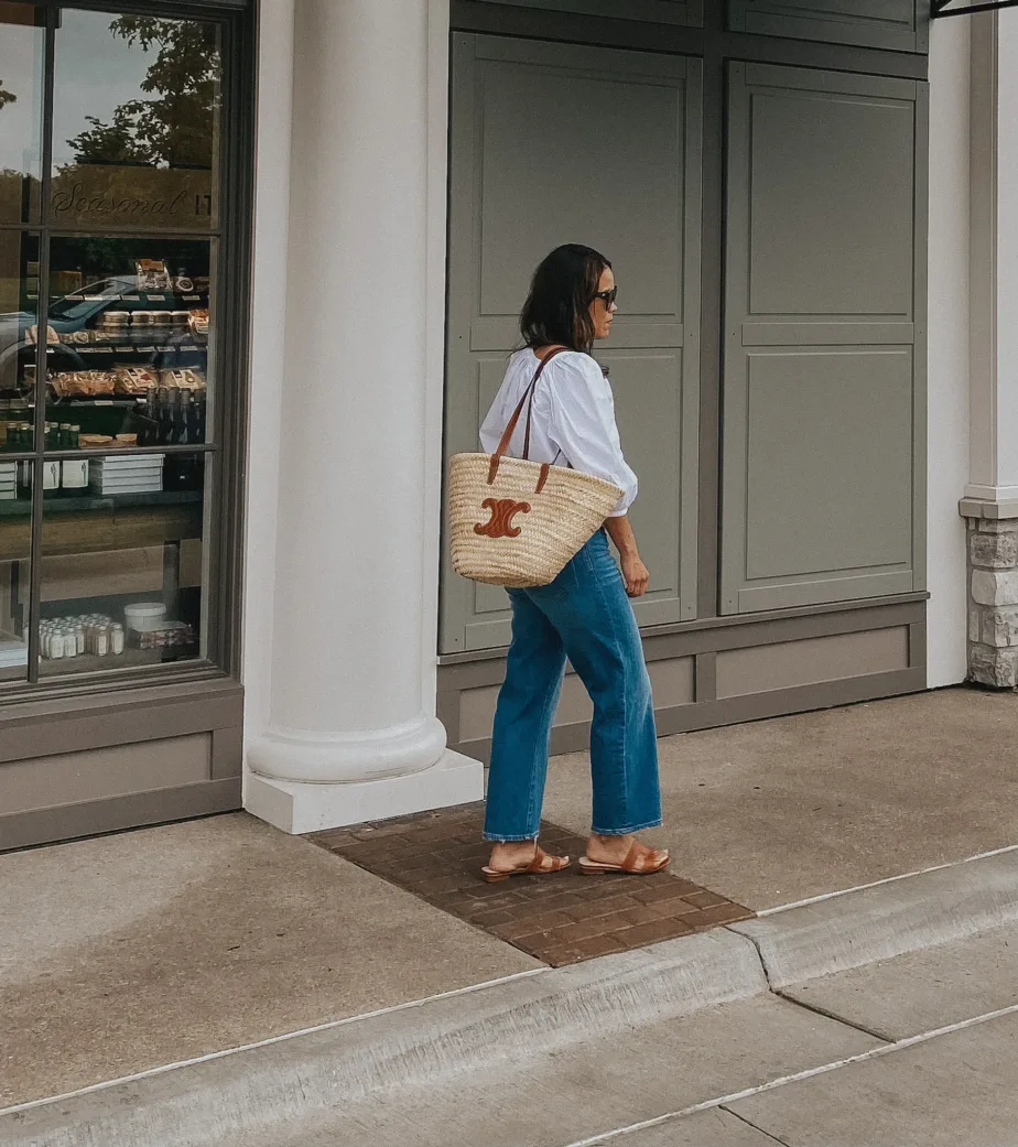 Girl in white top wearing crop jeans, sandals, and market tote.