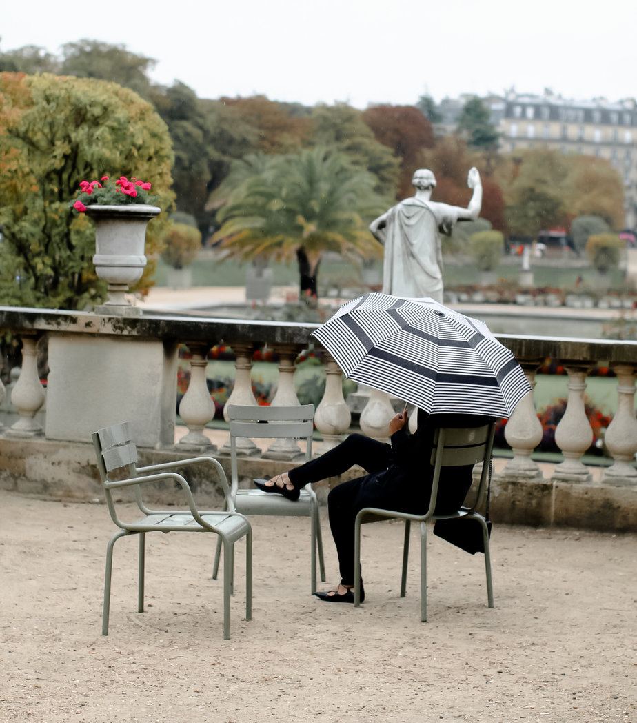 sitting in paris park with umbrella 