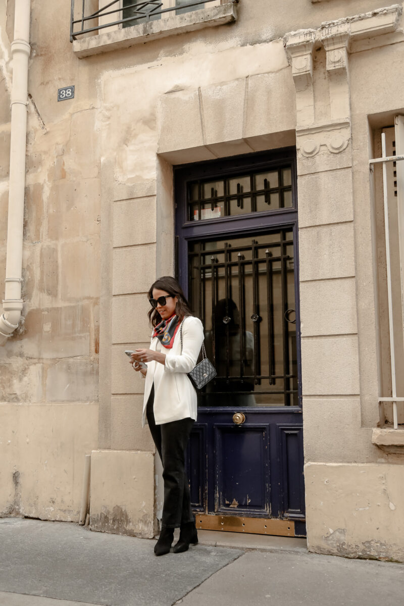 wearing white blazer and black jeans with boots in Paris