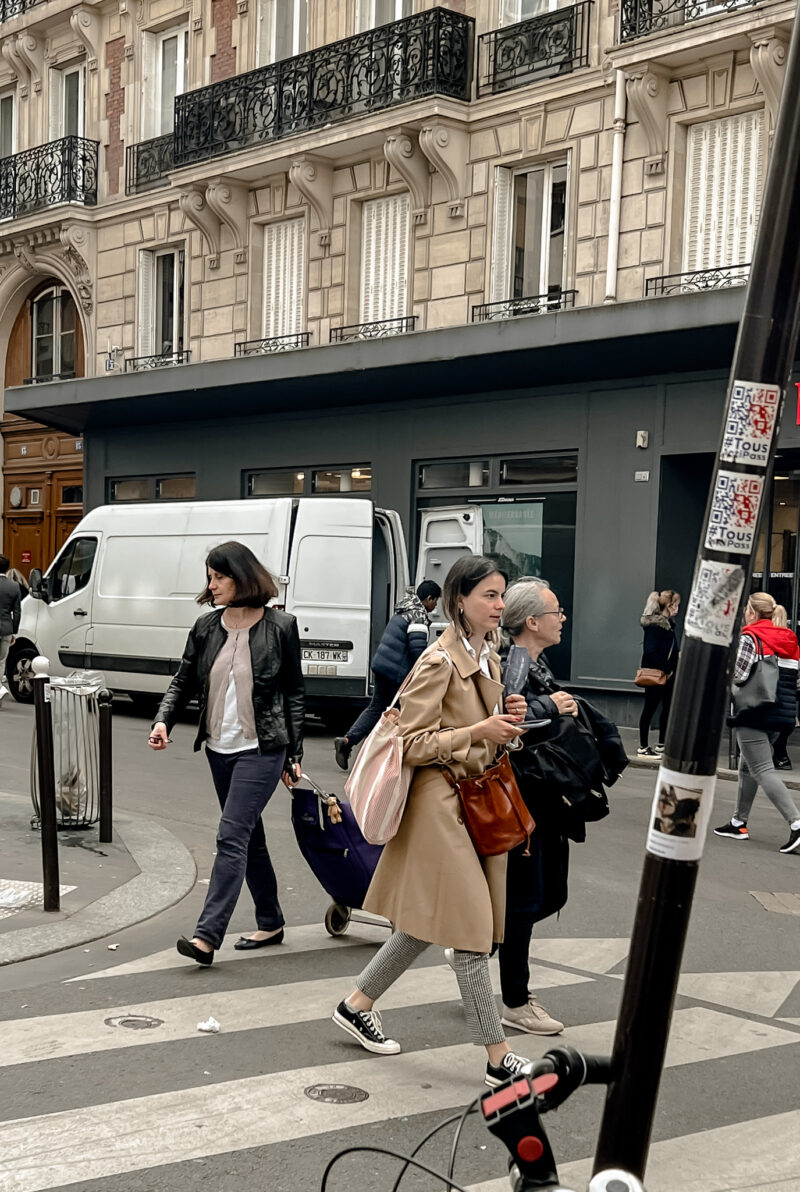 woman with trench and brown purse walking in Paris