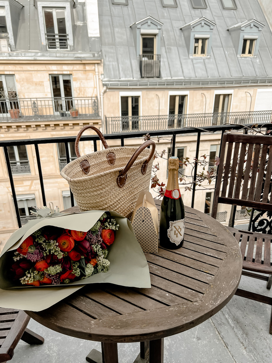 flowers on a patio with champagne bottle and basket bag