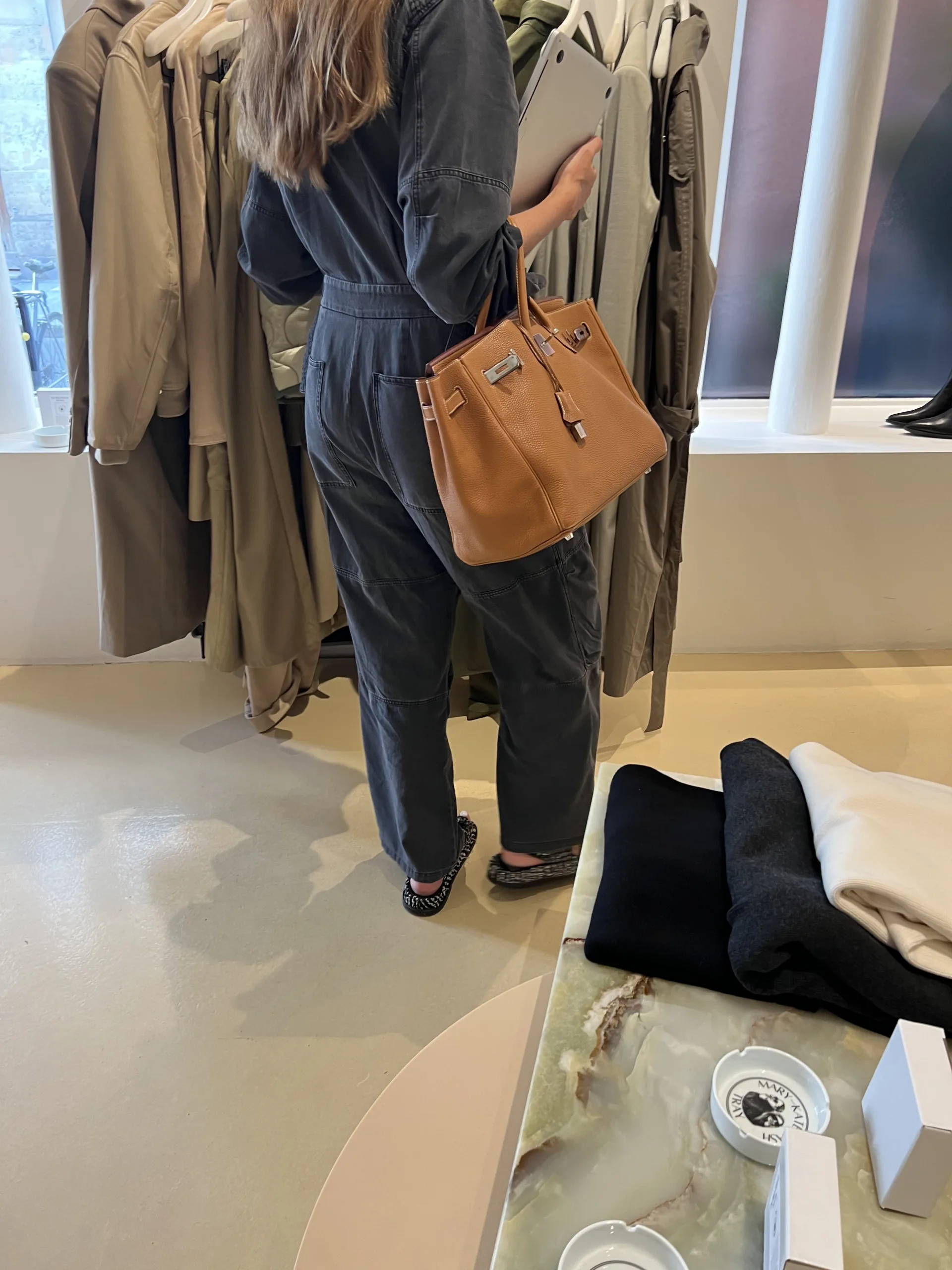 Woman wearing jumpsuit and carrying Hermes Birkin Bag.