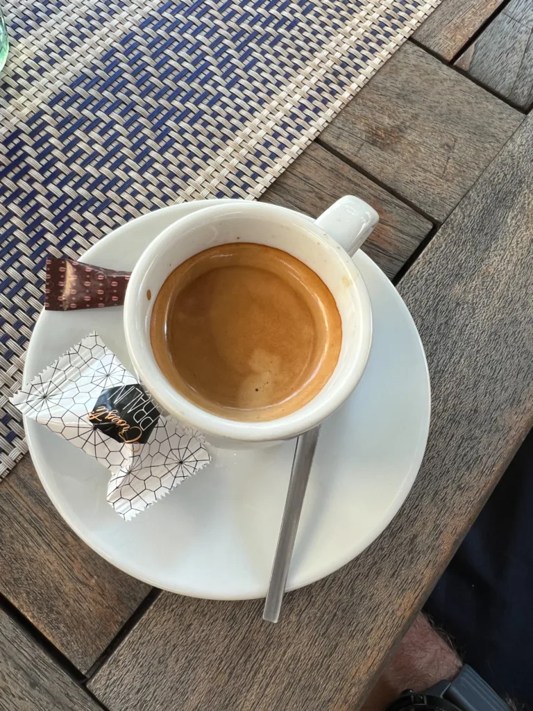 Un Noisette, espresso with cream sitting in an espresso cup with saucer on a table.