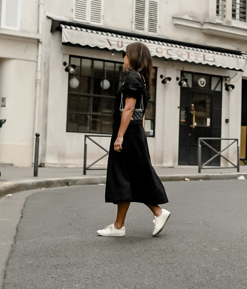walking on a street with black dress and white sneakers