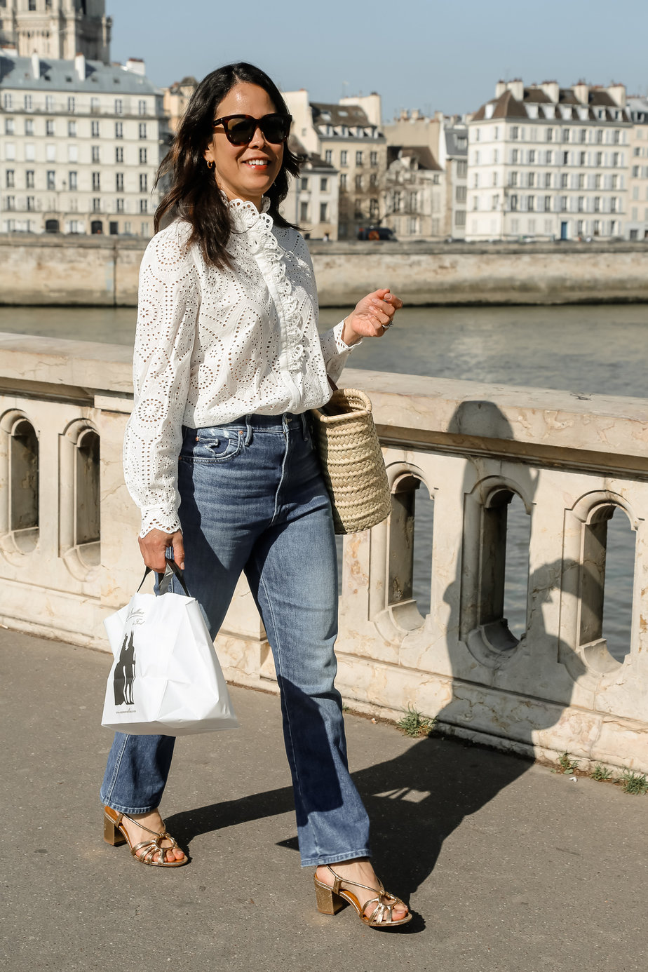 wearing white blouse and jeans walking over bridge in paris
