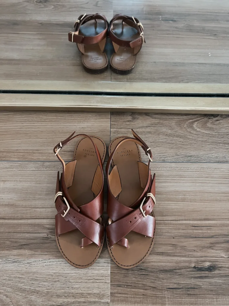 Brown and gold sandals sitting on the floor.
