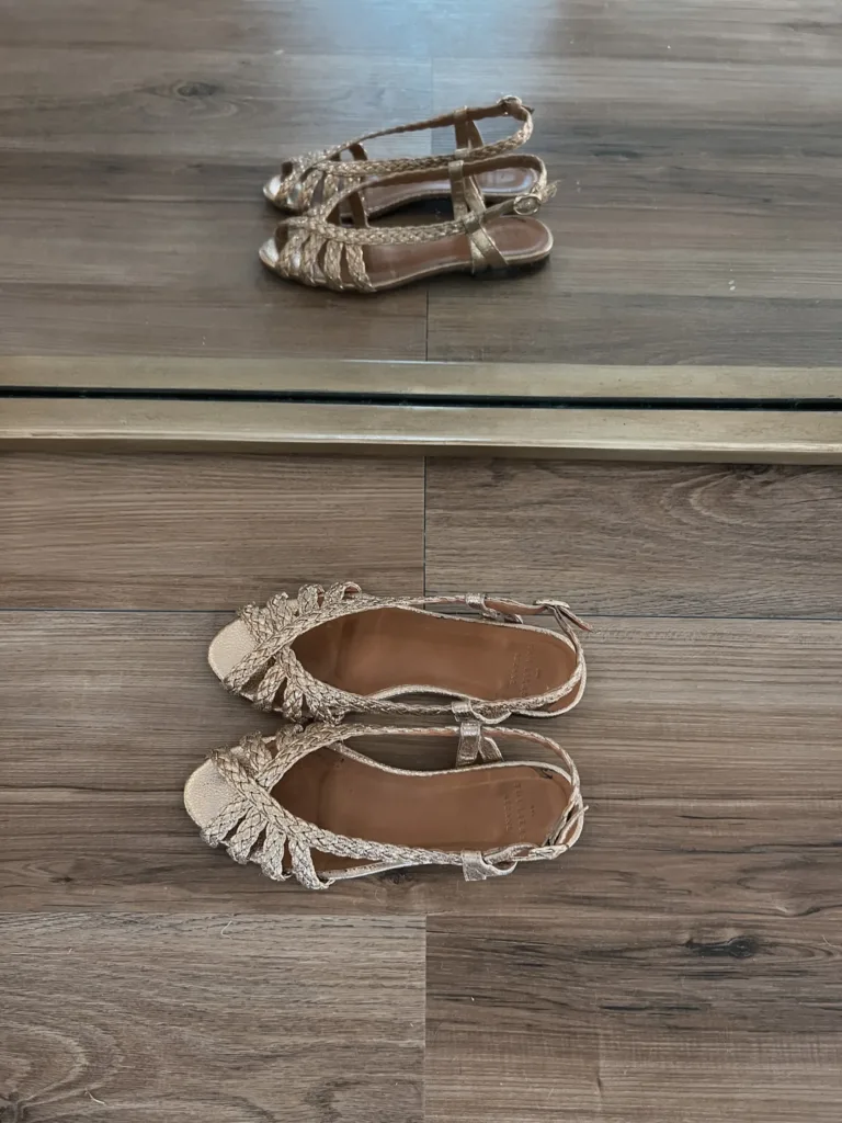 Sezane gold sandals sitting on the floor.