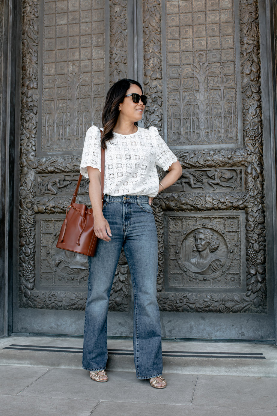 Wearing Sezane Serge Jeans With White Top And Sandals Against A Door