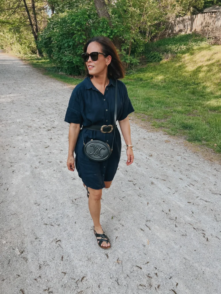 linen dress black bag Woman walking on gravel with linen dress black bag and black sandals.