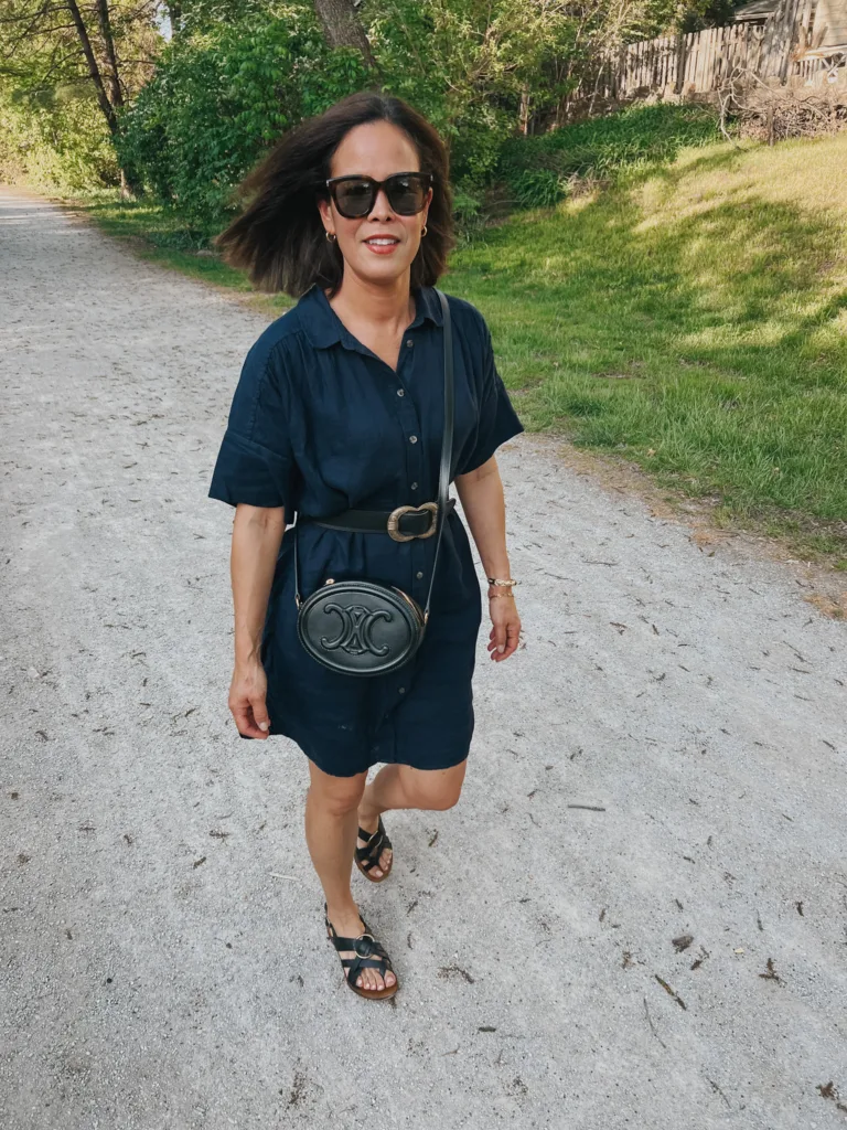navy linen dress Woman wearing navy linen dress with belt around waist and black sandals.