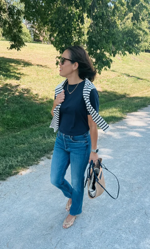 jeans navy t-shit outfit Woman walking and wearing jeans, navy t-shit, sweater over shoulders and sandals.