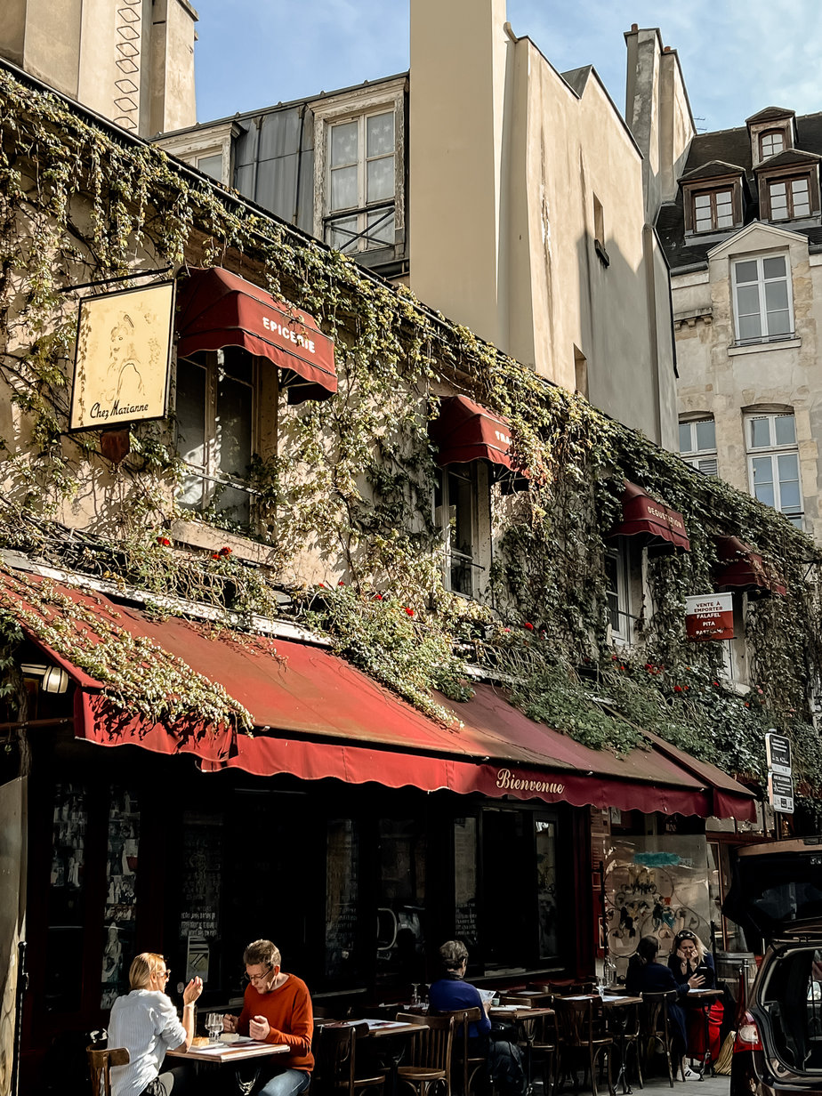 Cafe with ivy, red awning, in Paris in the Marais